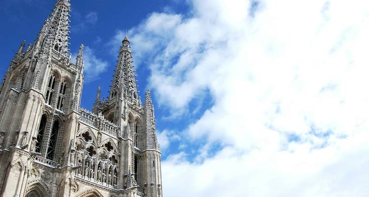 De hoge gotische torens van de Burgos-kathedraal steken af tegen een heldere lucht met hier en daar wat wolken.