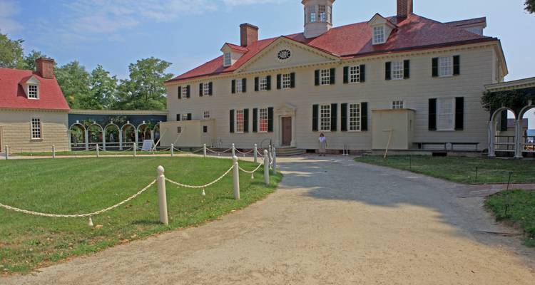 La maison Mount Vernon de George Washington, avec son toit rouge et son dôme, se dresse au-delà d'une allée de sable et d'une pelouse soignée.