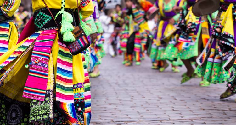 People in vibrant traditional costumes dancing on a cobblestone street.