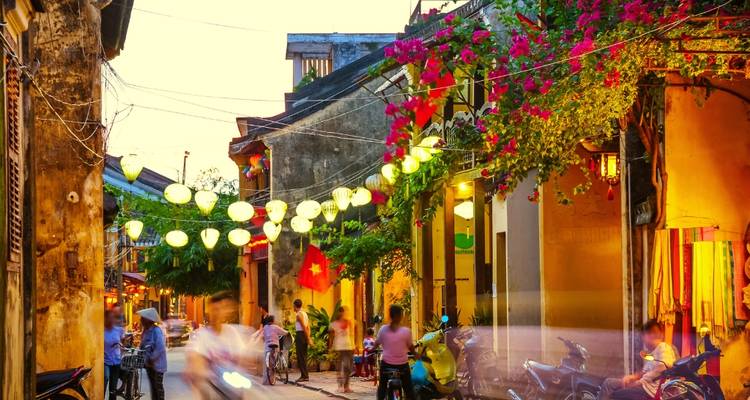 Scène de rue animée avec des lanternes et des drapeaux.