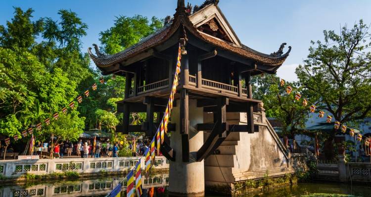 Temple avec des drapeaux dans un jardin luxuriant, personnes visibles.