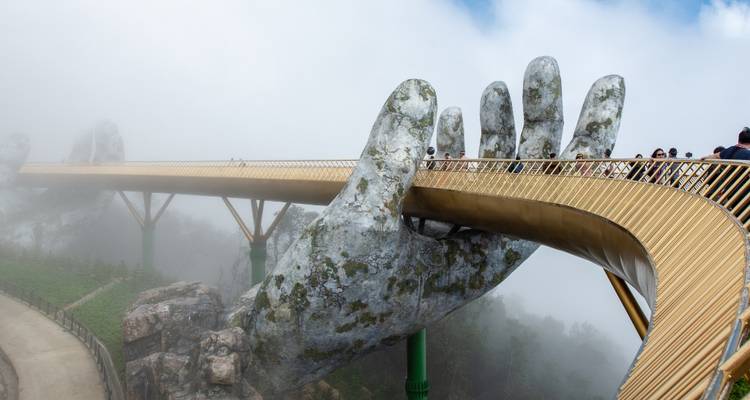 Pont doré soutenu par des mains géantes enveloppées de brume.