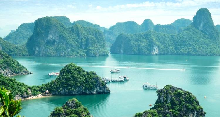 Vue aérienne de la baie d'Ha Long avec des bateaux et des îles calcaires.