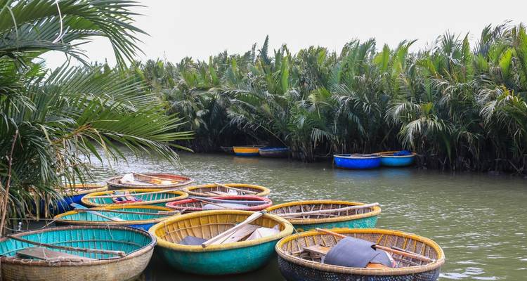 Des bateaux ronds en bambou dans une rivière avec une végétation luxuriante.