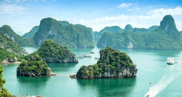 Vue de la baie d'Halong avec des bateaux et des îles verdoyantes.