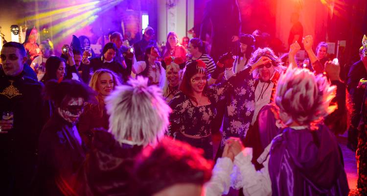 Un groupe de personnes en costumes à une fête avec des lumières colorées.