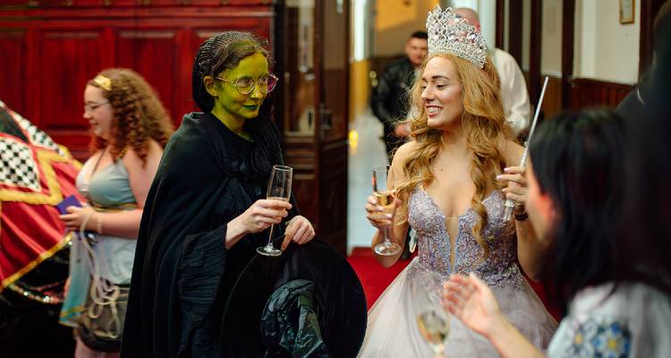 Deux personnes en costume tenant des boissons à une fête.