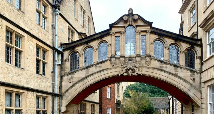 Bâtiments historiques en grès reliés par le pont des Soupirs orné d'arches dans une allée de collège.