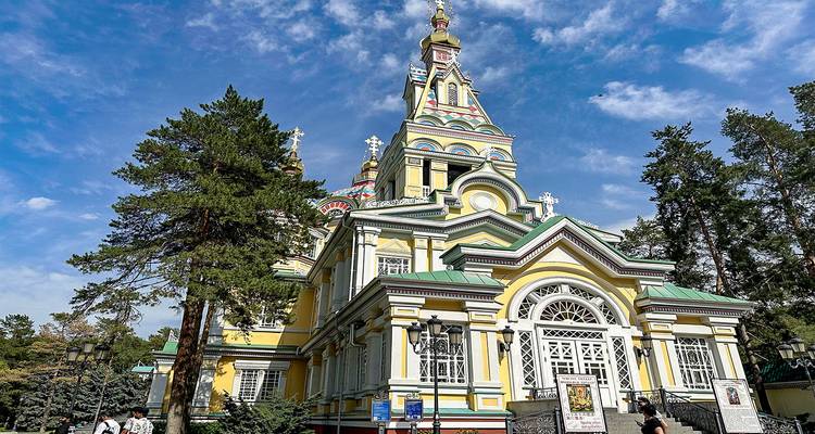 Ornate yellow and white cathedral surrounded by trees.