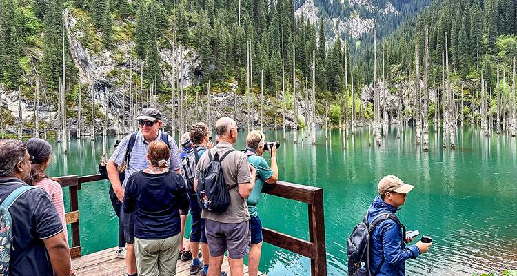 Tourists taking photos at a picturesque mountain lake.