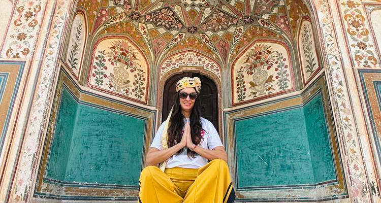 Vrouw zittend met gekruiste benen voor een kleurrijk sierlijk ontwerp.