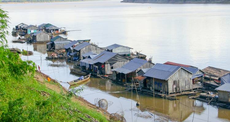 Schwimmende Dorfhäuser am Fluss mit Menschen in Booten