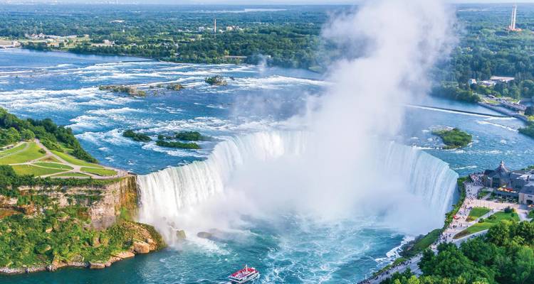 Vista aérea de las Cataratas Herradura en las Cataratas del Niágara con niebla elevándose y un bote de tours debajo.