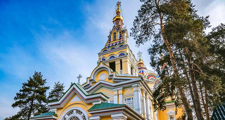 Colorful cathedral facade with surrounding pine trees.