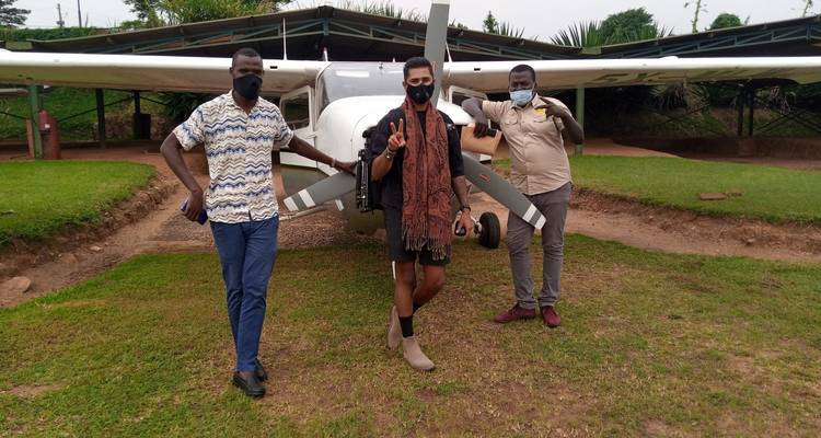 Trois personnes posant devant un petit avion garé sur l'herbe.