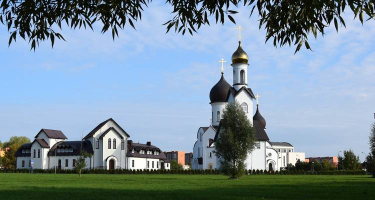 Weiße Kirche mit goldenen Kuppeln in einem grünen Feld.