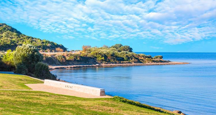 Coastal view with memorial wall and greenery.