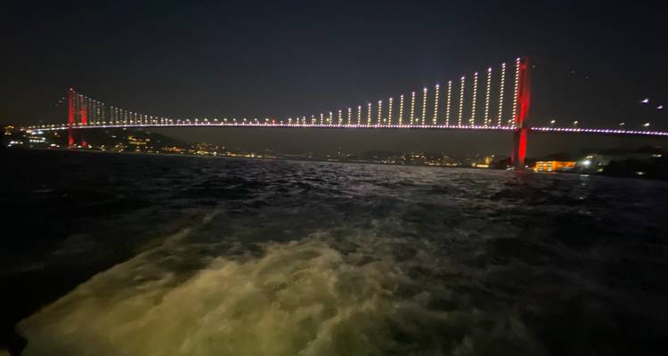 Bridge illuminated at night over a body of water.
