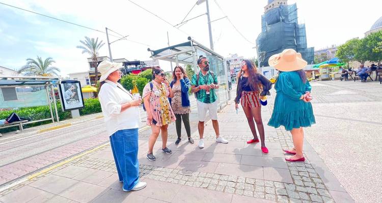 Groep toeristen die staan in een zonnige stedelijke omgeving met een tramhalte.