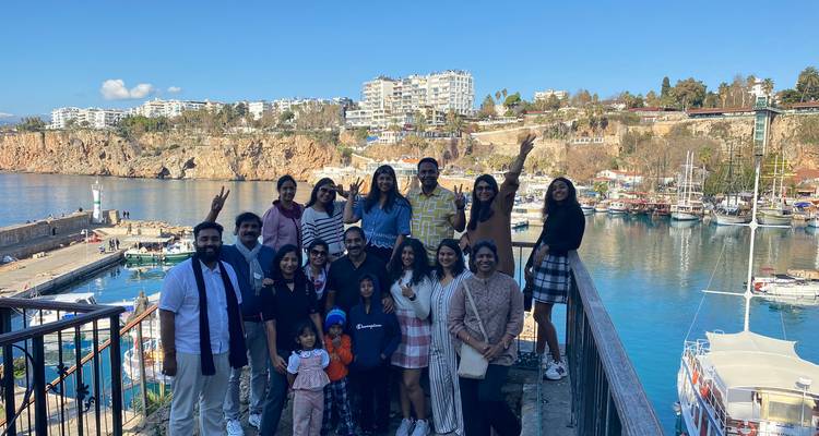 Groep poseert op een balkon met een jachthaven op de achtergrond.