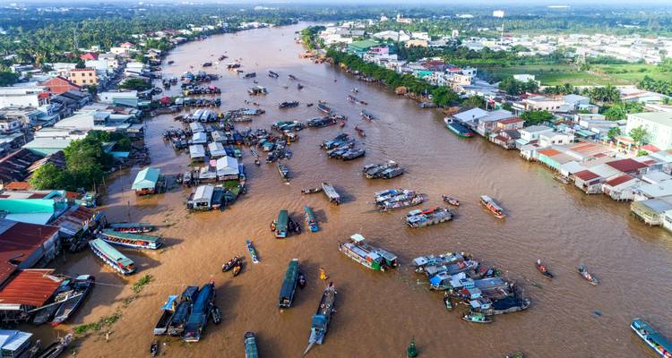 Aerial view of a bustling river with numerous boats and houses lining the riverbank.