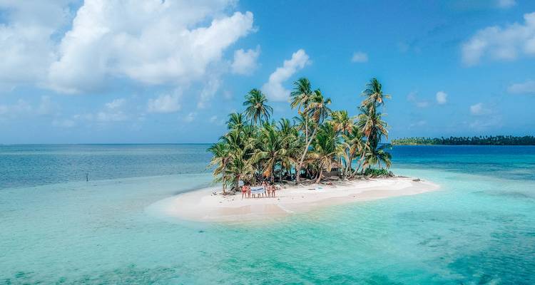 Petite île de sable avec des palmiers et des gens qui se détendent.