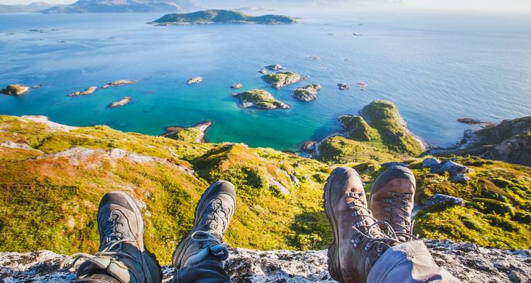 Randonneurs profitant d'une vue sur la mer depuis une falaise avec de nombreuses petites îles.