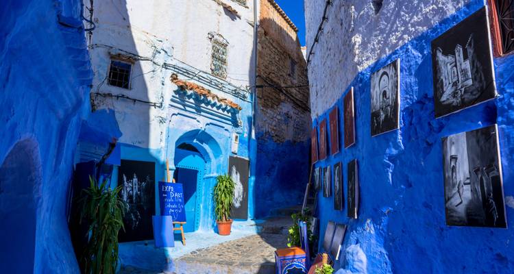 Une ruelle bleue à Chefchaouen remplie d'œuvres d'art colorées.