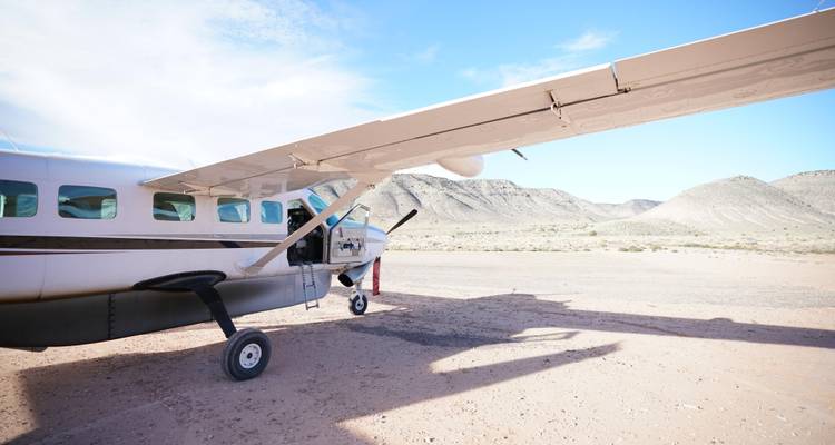 Klein vliegtuig geparkeerd op een landingsbaan in de woestijn.