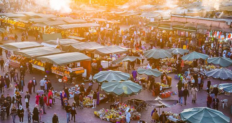 High view of the bustling Jemaa el-Fna night market glowing under golden sunset haze.