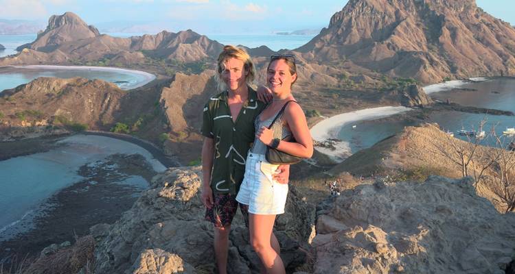 Paar posiert auf einer Klippe mit Blick auf eine Bucht und Hügel.