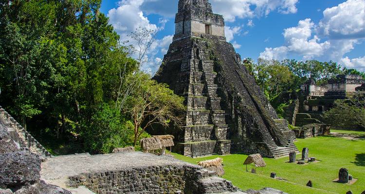 Ruinas mayas en un entorno verde exuberante con visitantes.