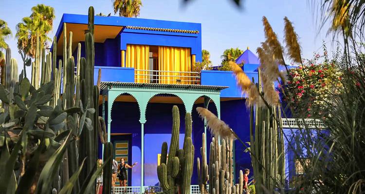 Villa de un brillante azul cobalto del Jardin Majorelle rodeada de altos cactus y palmeras.