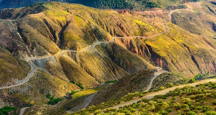 El sinuoso camino de montaña se retuerce a través de las laderas multicolores de la cordillera del Alto Atlas.