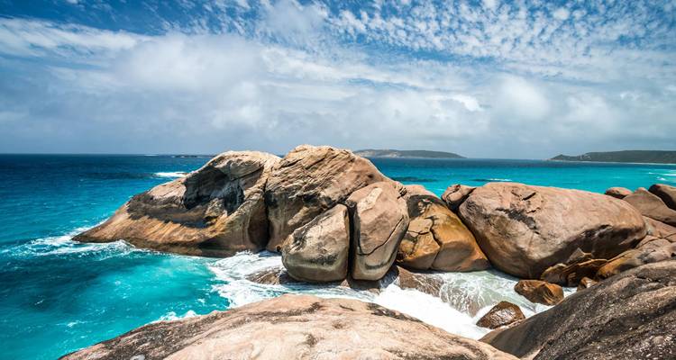 Zerklüftete Granitfelsen und elektrisch blaue Wellen prallen an einer abgelegenen Küstenlinie Westaustraliens aufeinander.
