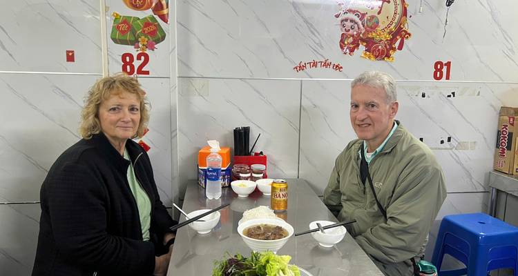 Deux voyageurs assis à une petite table de restaurant de nouilles vietnamien avec des bols fumants de pho
