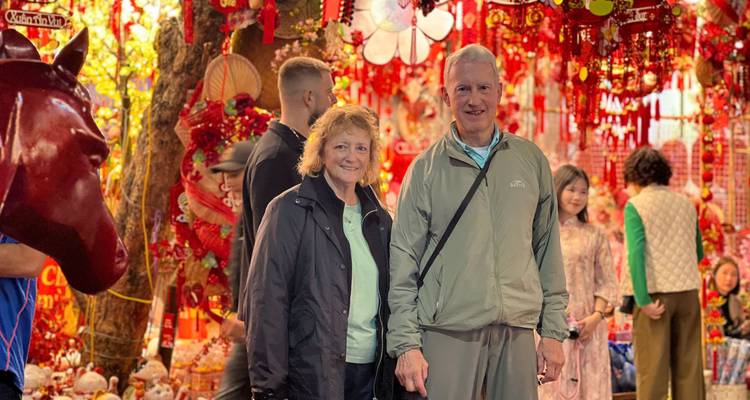 Les voyageurs se tiennent au milieu de décorations rouges vives du Têt dans un étal de marché animé de Hanoï
