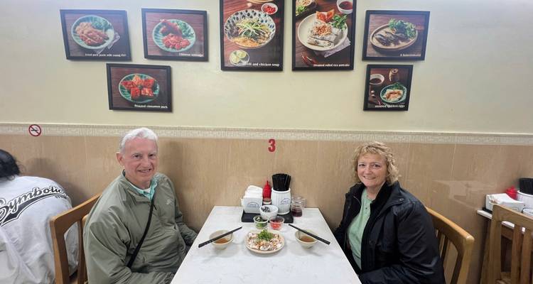 Couple dînant dans un restaurant vietnamien local avec des photos encadrées de plats sur le mur