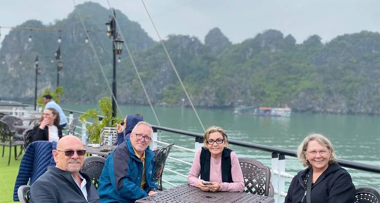 Répéter l'angle du groupe se détendant sur le pont du bateau de croisière de la baie d'Halong avec des îles calcaires en arrière-plan
