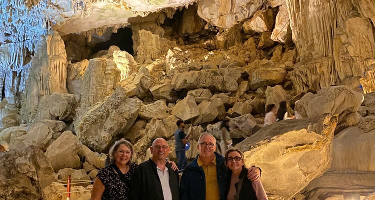 Groupe de voyageurs posant à l'intérieur d'une grotte calcaire illuminée avec des stalactites spectaculaires dans la baie d'Halong