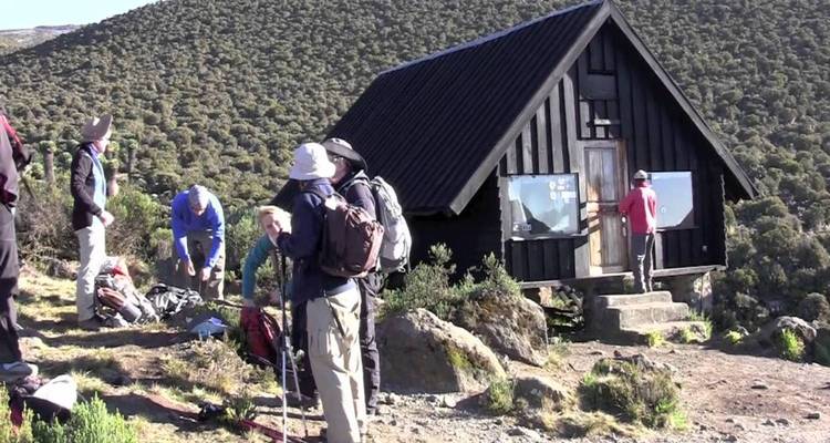 Eine Gruppe von Menschen versammelte sich in der Nähe einer kleinen Hütte am Berghang.