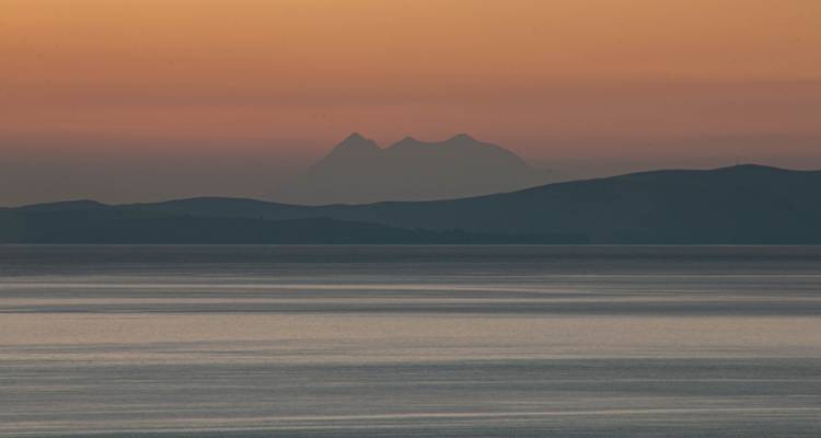 Lever ou coucher de soleil sur un lac avec des montagnes au loin.