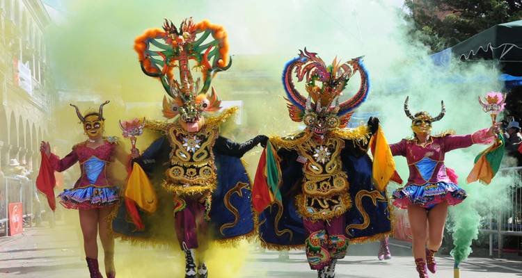 Des gens en costumes colorés lors d'un festival avec des effets de fumée.