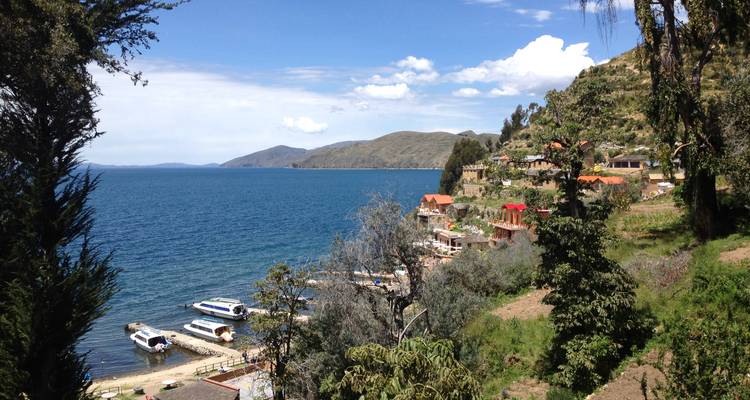 Vue d'un lac tranquille avec un petit village et des bateaux.