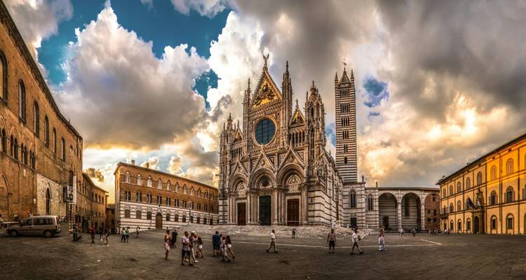 Vue panoramique de la cathédrale de Sienne et de la place environnante sous un ciel nuageux dramatique.