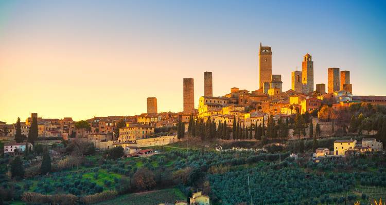 Vue panoramique du coucher de soleil sur San Gimignano avec une lumière dorée sur ses tours.