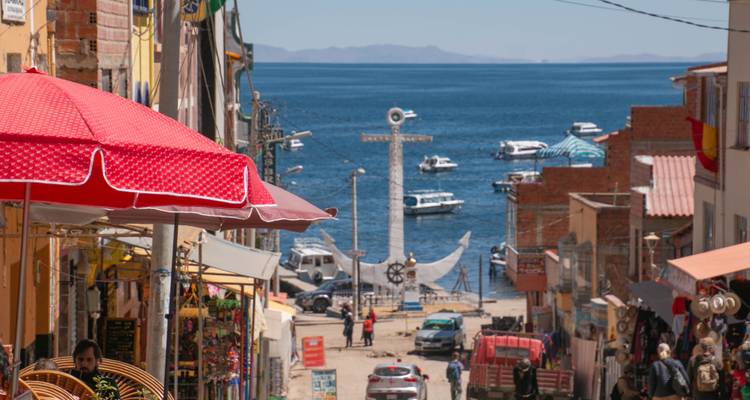 Mercado callejero frente a un lago con botes bajo sombrillas