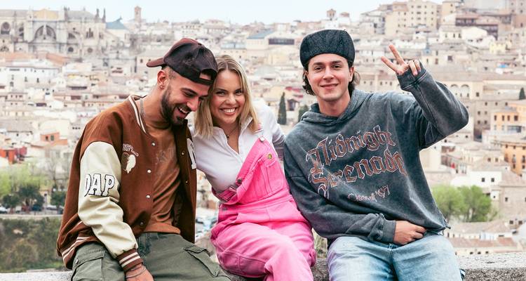 Trois amis souriants avec l'horizon historique de Tolède qui s'étend derrière eux.