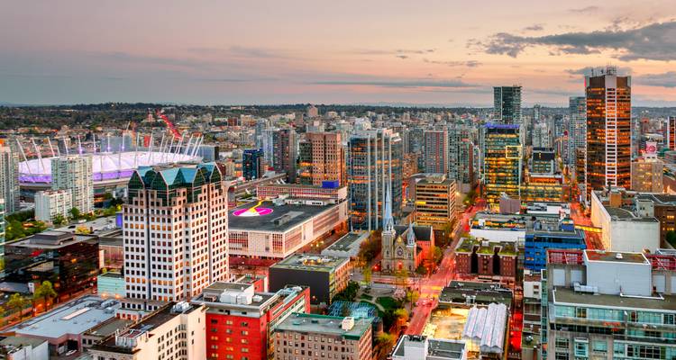 Vista aérea de una ciudad moderna con un estadio iluminado al atardecer.