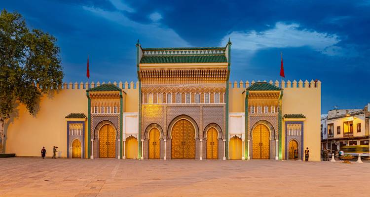 Les portes illuminées du Palais Royal à Meknès contre le ciel du soir bleu profond